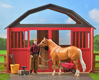 Breyer horses play inside a red two-stall large barn.